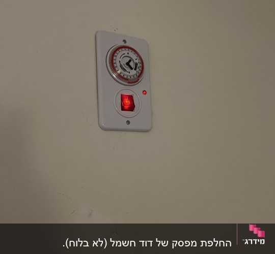 מתג טיימר על קיר עם נורית חיווי אדומה